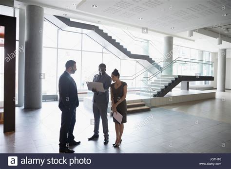 Business people talking, using laptop in modern office lobby Stock Photo - Alamy