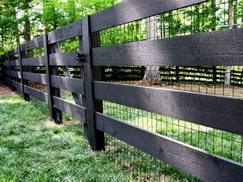 Black wire-mesh fencing is attached to four-by-four sawn board fencing ...