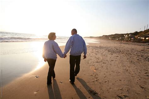 Elderly Couple Holding Hands And Walking On The Beach | Stocksy United