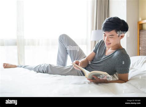 Young man reading book on bed Stock Photo - Alamy