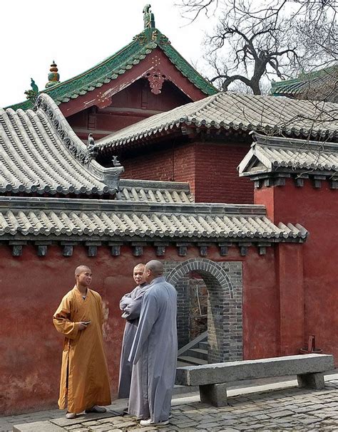 two men standing in front of a red building with roof tiles on the top ...