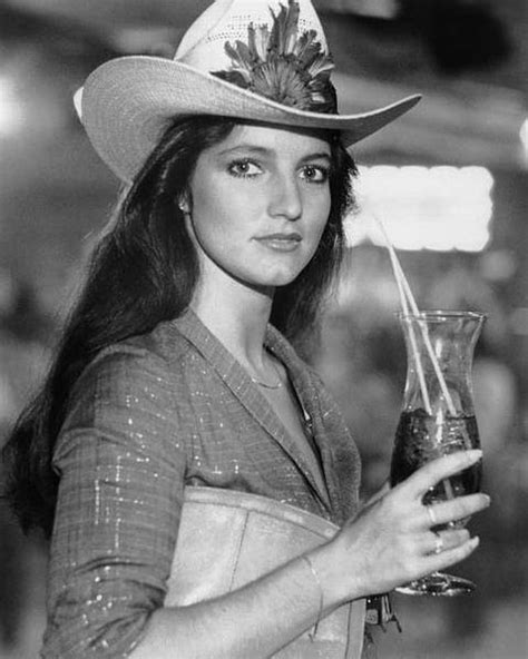 a woman in a cowboy hat holding a drink