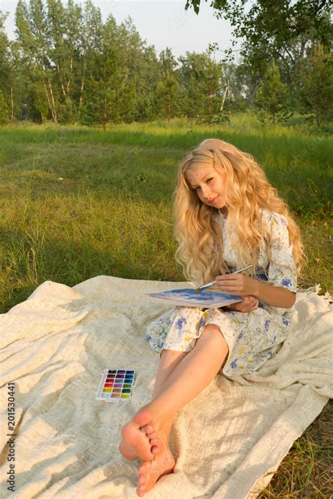 Beautiful charming barefoot long curly blonde hair teenage girl wearing a long light dress ...