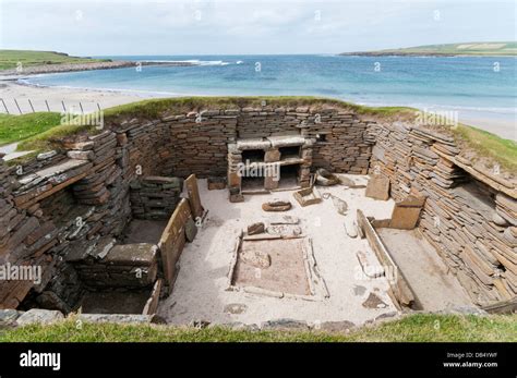 House 1 at Skara Brae Neolithic Village on Mainland Orkney with the Bay of Skaill in the ...