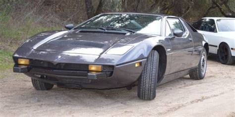 two cars parked on the side of a dirt road next to trees and bushes,