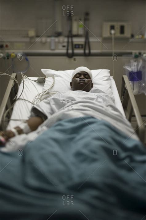 Boy in hospital bed with head bandages stock photo - OFFSET