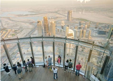 people standing on top of a tall building looking down at the city from ...