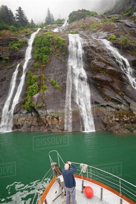 Man taking a picture of waterfalls from a boat, Endicott Arm, Alaska ...