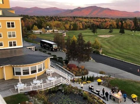 people are walking around in front of a yellow building with mountains in the back ground