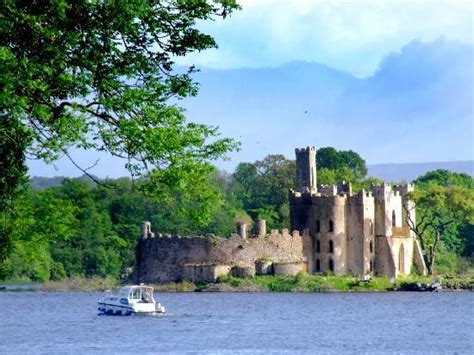 a boat is on the water in front of an old castle with trees around it