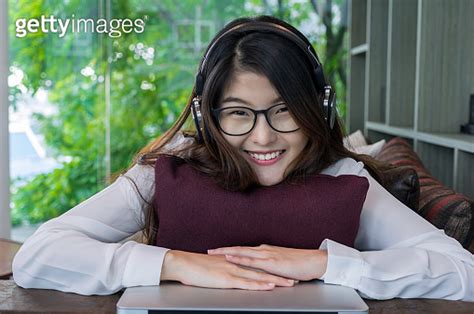 Portrait of smiling asian beautiful young businesswoman listening the music with Earphone in the ...