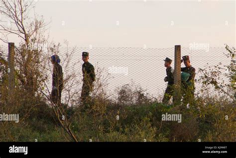 North Korean Military walk the border fence on the Yalu river near the Chinese border Stock ...