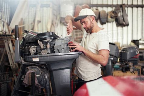 Man repairing outboard motor in boat repair workshop - Stock Photo - Dissolve