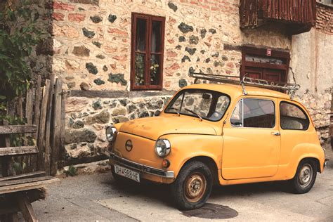 Yellow Nissan Classic Car Beside Gray Beige Concrete Building · Free Stock Photo