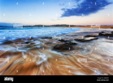 Incoming blurred wave on rocks and boulders of Curl Curl beach Sydney ...