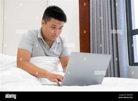 Asian man working on bed Stock Photo - Alamy