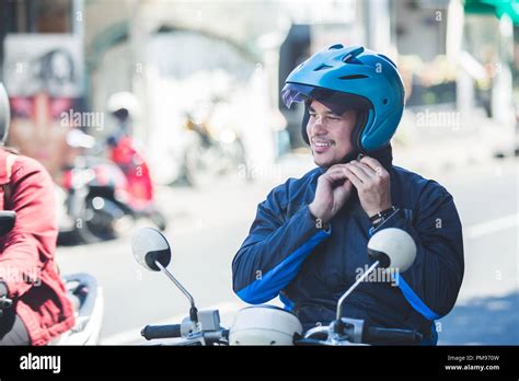 motorcycle taxi driver fastening his helmet for safety riding Stock Photo - Alamy