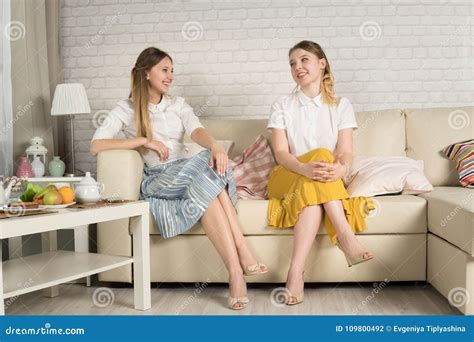 Two Young Girls are Sitting on the Couch Stock Photo - Image of sofa, sitting: 109800492