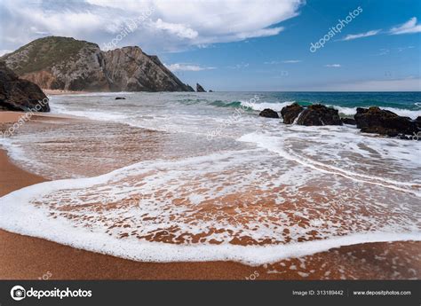 Praia da Adraga at atlantic ocean, Portugal. Foamy wave at sandy beach ...