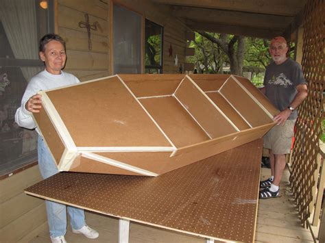 two men standing next to each other holding up a large cardboard boat ...