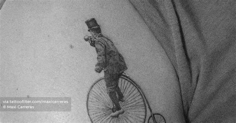 Micro-realistic penny-farthing tattoo on the shoulder.