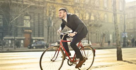 Man In Black Suit Riding Bicycle Down The Street · Free Stock Photo