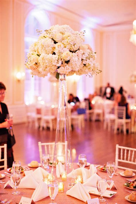 The centerpieces were tall, inverted trumpet glass vases with a round bouquet of white roses ...