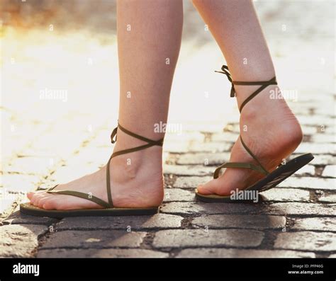 Wearing sandals on pair of female feet walking on cobbled stone pavement, low section Stock ...