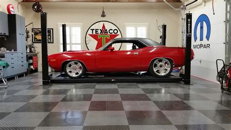 a red car is being worked on in a garage with checkered tile flooring