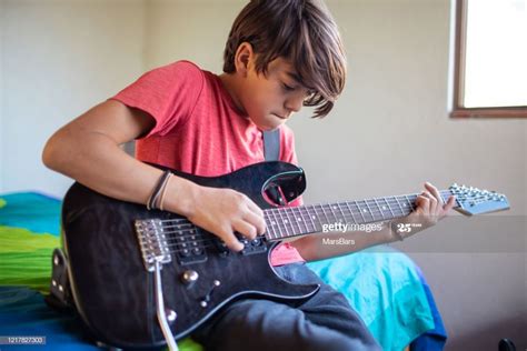 Latinx pre-adolescent child learning to play electric guitar at home ...