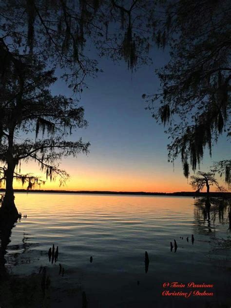 the sun is setting over water with trees