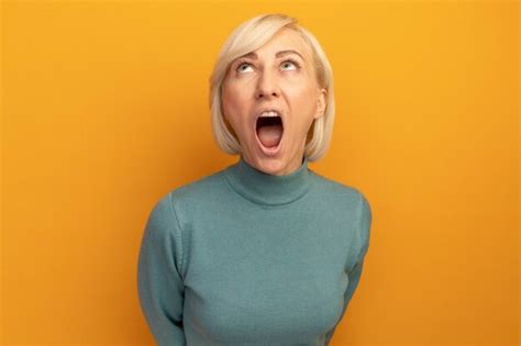 Free Photo | Annoyed pretty blonde slavic woman looks up isolated on orange wall