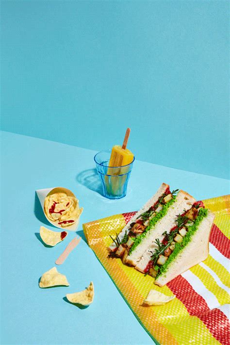 a sandwich sitting on top of a yellow towel next to chips and a drink in a glass