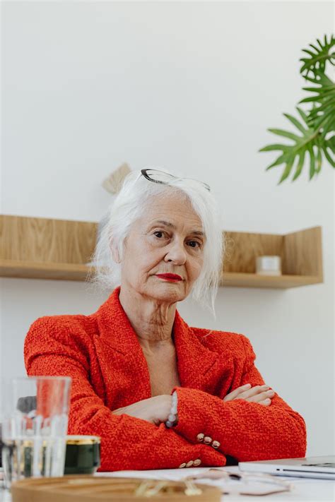 Elderly Woman in Orange Blazer Sitting Behind an Office Table · Free Stock Photo