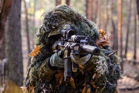 Sniper aiming from his rifle in forest/Portrait of sniper in the woods ...