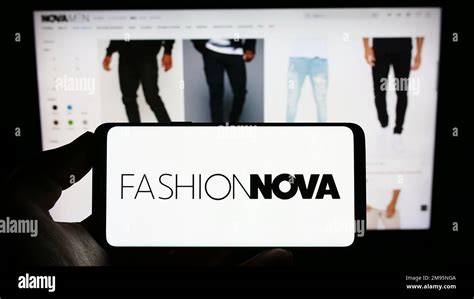 Person holding cellphone with logo of US e-commerce company Fashion Nova Inc. on screen in front ...