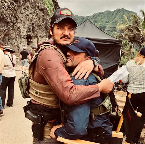 two men hugging each other while standing in front of a mountain with people around them