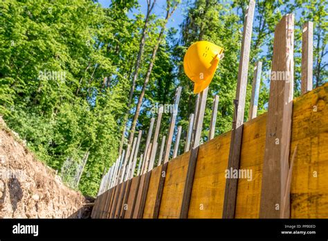 Bright Yellow Hard Hat Hanging on Post of Unfinished Building Foundation Under Construction in ...