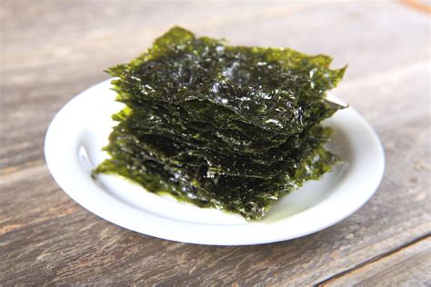 a white plate topped with seaweed on top of a wooden table