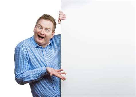 Young man making funny face, holding a blank sign board. Studio shot on white background ...