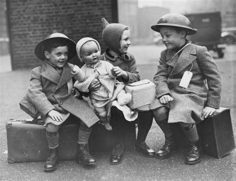 Three young evacuees sit on their suitcases ready for their journey ...