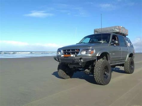 the truck is parked on the beach near the water