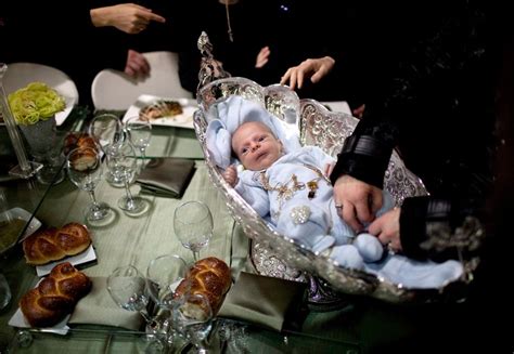 An Ultra Orthodox Jewish mother decorates a new born baby with silver jewelry in a silver bowl ...