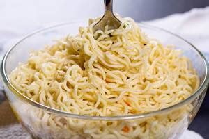 White tureen on a blue background with ingredients for a quick lunch. Raw instant noodles ...