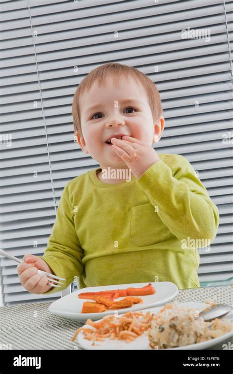 Baby boy feeding himself at dining table Stock Photo - Alamy