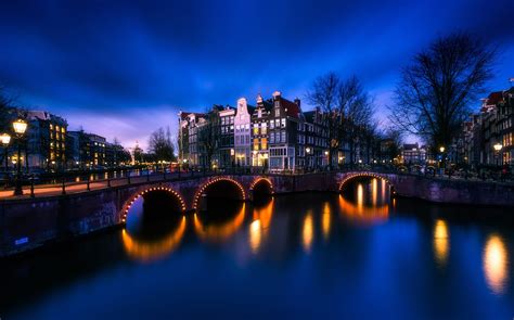 Photo of town lights reflecting on body of water during nighttime ...