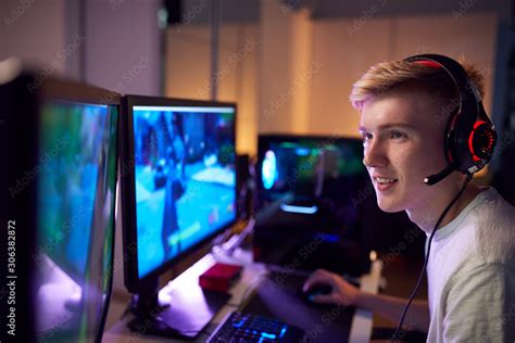 Teenage Boy Wearing Headset Gaming At Home Using Dual Computer Screens ...