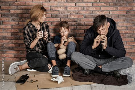 Poor homeless family sitting on floor near brick wall Stock Photo ...