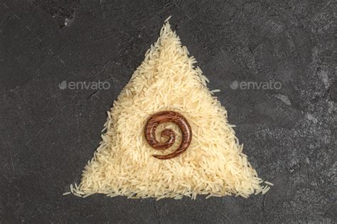 top view raw rice forming triangle shape on the dark background food ...