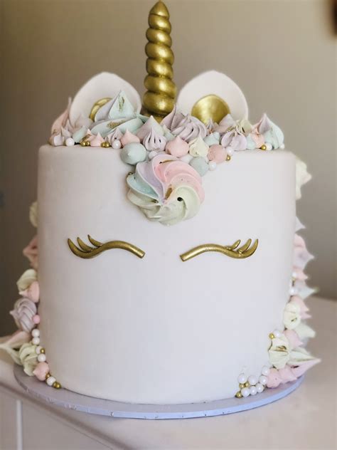 a white cake decorated with flowers and a gold unicorn horn on top of it's head